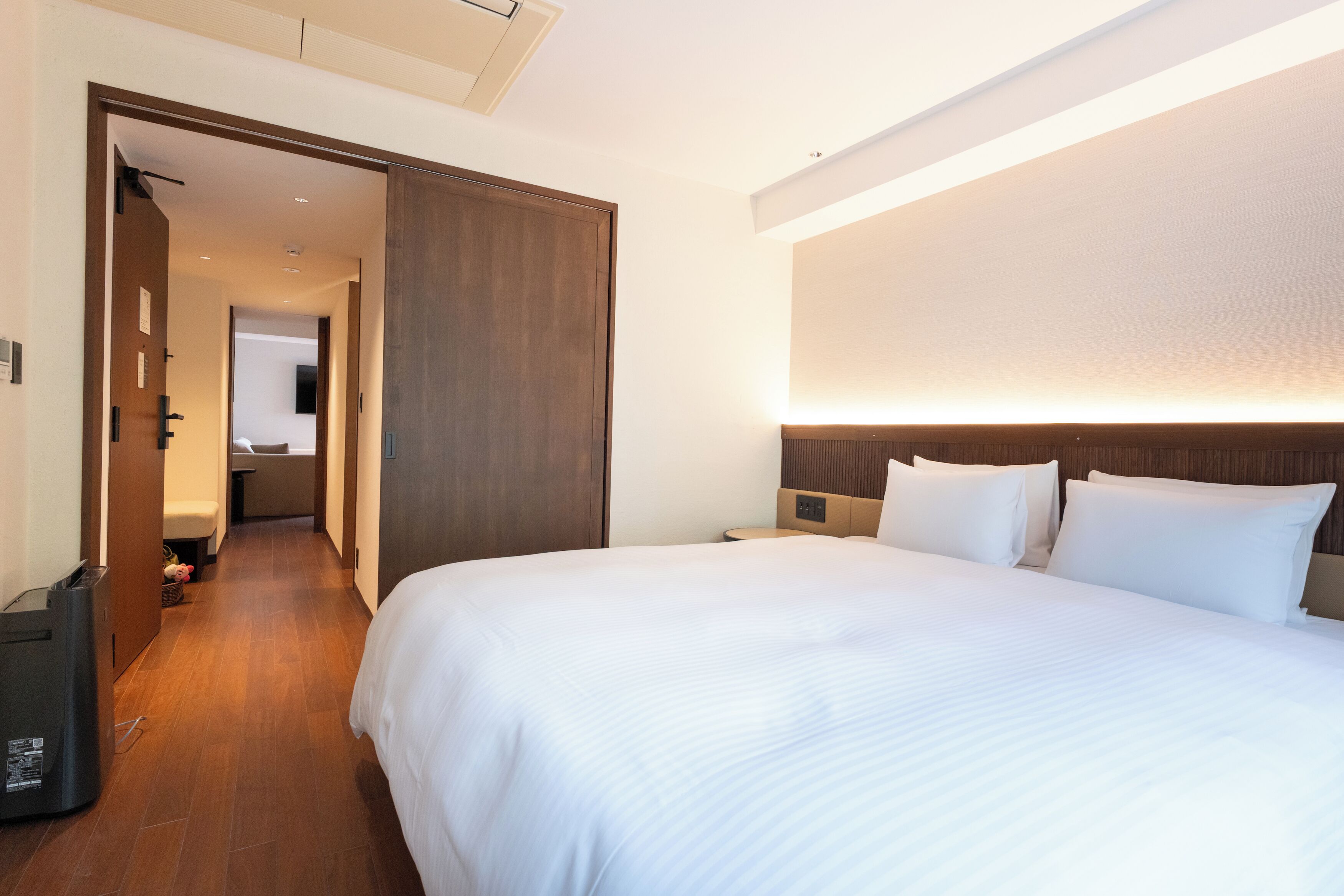 A hotel room with a large bed, a wooden headboard, a bedside table, and a nightstand.