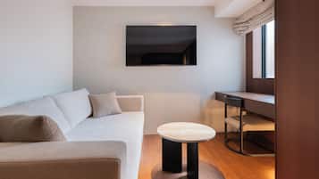 Ein modernes Wohnzimmer mit einer Couch, einem kleinen runden Tisch und einem an der Wand befestigten Fernseher.