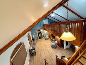 A spacious loft with a high ceiling, wooden beams, a staircase, and a seating area with a sofa and armchairs. -     Balti Bay Loft -Beach & Boating Getaway Downtown New Baltimore  -Sleeps 11 (New Baltimore)