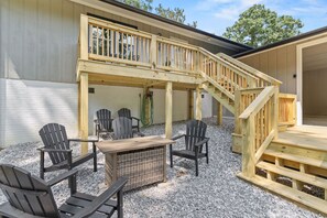 Un espacio de estar techado al aire libre con mesa y sillas de madera, una escalera y una pérgola.
