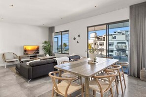 Una sala de estar moderna con sofá, televisión, mesa de comedor y sillas.