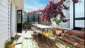 Eine Terrasse mit Tisch und Stühlen, einem Blumentopf und einer Backsteinmauer.