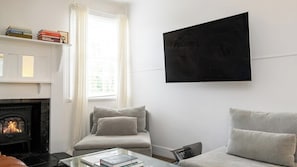 A living room with a fireplace, a sofa, a coffee table, and a television mounted on the wall. - Sisteron | Daylesford (Daylesford)