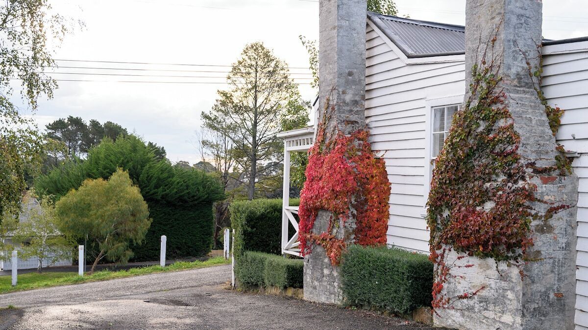 Ein Haus mit einem Kiesweg, einem weißen Zaun und einer gepflegten Hecke.