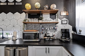 Eine moderne Küche mit einer Kaffeobar, einer Cuisinart-Mikrowelle, einer Keurig-Kaffeemaschine und einer Uhr, die 8:00 Uhr anzeigt.