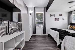 Een slaapkamer met een bed, bureau en een raam met gordijnen.