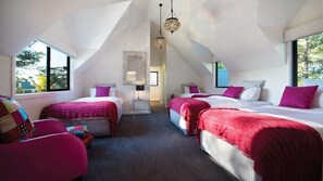 Ein Schlafzimmer mit zwei Betten, einem Sessel und einem Spiegel.