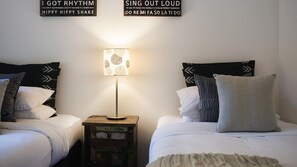 A hotel room with two beds, a bedside table with a lamp, and wall decorations. - Artemis Retreat Daylesford (Daylesford)