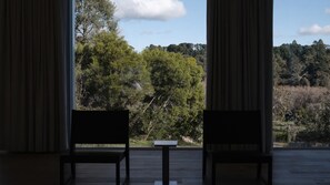 Ein Zimmer mit zwei Stühlen, das auf einen Wald ausblickt.