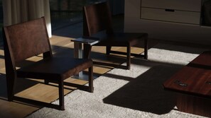 Una habitación con dos sillas de madera, una mesita y suelo alfombrado.