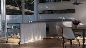 Eine moderne Küche mit Essbereich, großen Fenstern und Blick ins Freie.