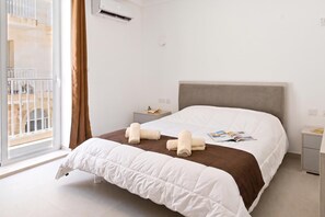 A hotel room with a large bed, a nightstand, a window with curtains, and a view of the outside. - Pool And Sea - Modern Apart Sannat Gozo, Sannat Ghawdex - Gozo, Malta (Sannat Ghawdex - Gozo)