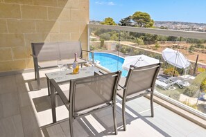 Ein Balkon mit Tisch und Stühlen mit Blick auf einen Pool und eine schöne Landschaft.