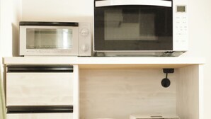 A kitchenette with a microwave, a coffee maker, and a toaster on a wooden countertop. - Neo Universal 01 (Osaka, Konohana, Nishikujo)