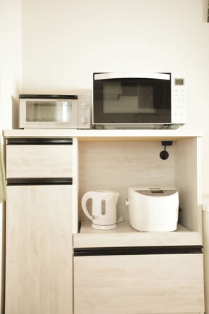 Eine Küchenzeile mit einer Mikrowelle, einer Kaffeemaschine und einem Toaster auf einer Holzausziehtafel.