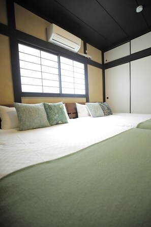 Ein Hotelzimmer mit Bett, Kissen, einem Fenster und einer Klimaanlage.