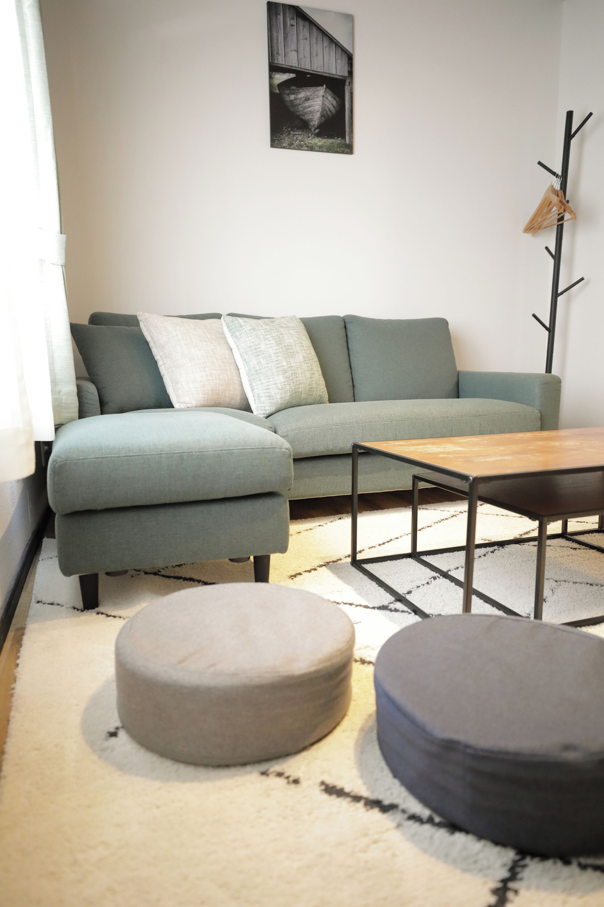 A modern living room with a sectional sofa, a coffee table, and two ottomans.