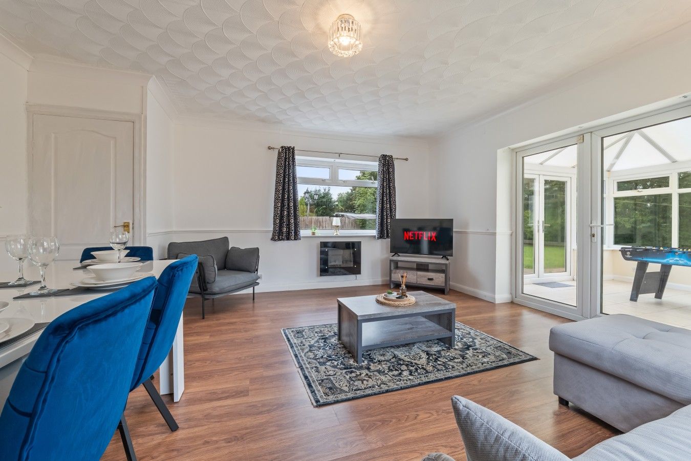 A modern living room with a dining area, a flat-screen TV, and a pool table.