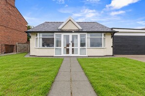 Een gelijkvloers huis met een veranda, een garage en een verzorgd gazon.