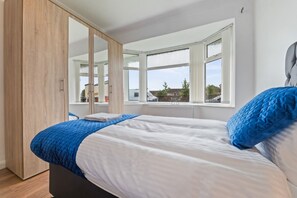 Een slaapkamer met een bed, een kast, een raam en uitzicht op het omliggende landschap.