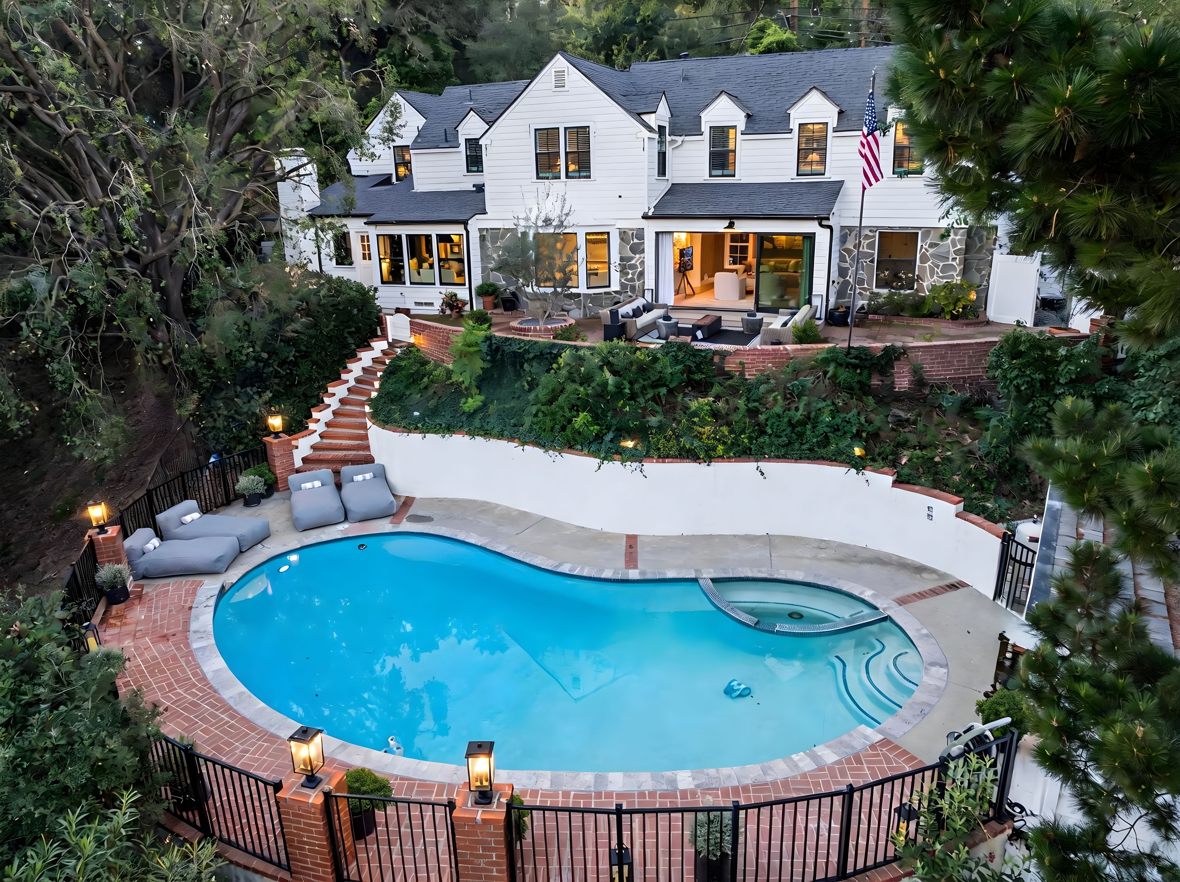 Ein zweistöckiges Haus mit Swimmingpool, Sitzgelegenheit im Freien und einem gepflegten Garten.