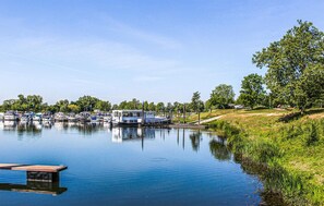 A calm lake with boats docked on the shore, surrounded by greenery and trees.