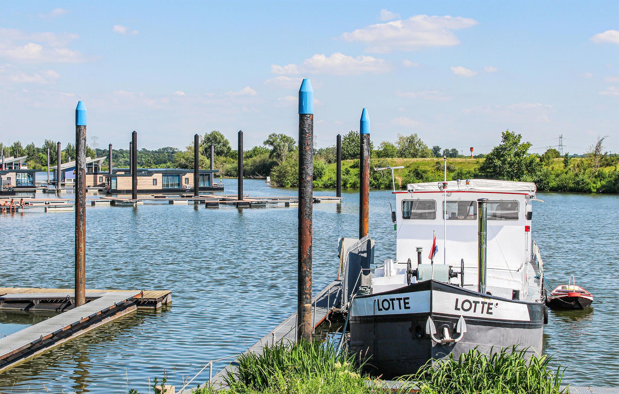 Un bateau nommé « LOTTE » a accosté à un quai, près d’une petite construction qui ressemblait à une maison et qui était située sur l’eau.