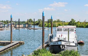 A boat named 'LOTTE' docked at a pier with a small house-like structure on the water. - Pet friendly ship in Ohé en Laak with house sea view (Ohé en Laak)
