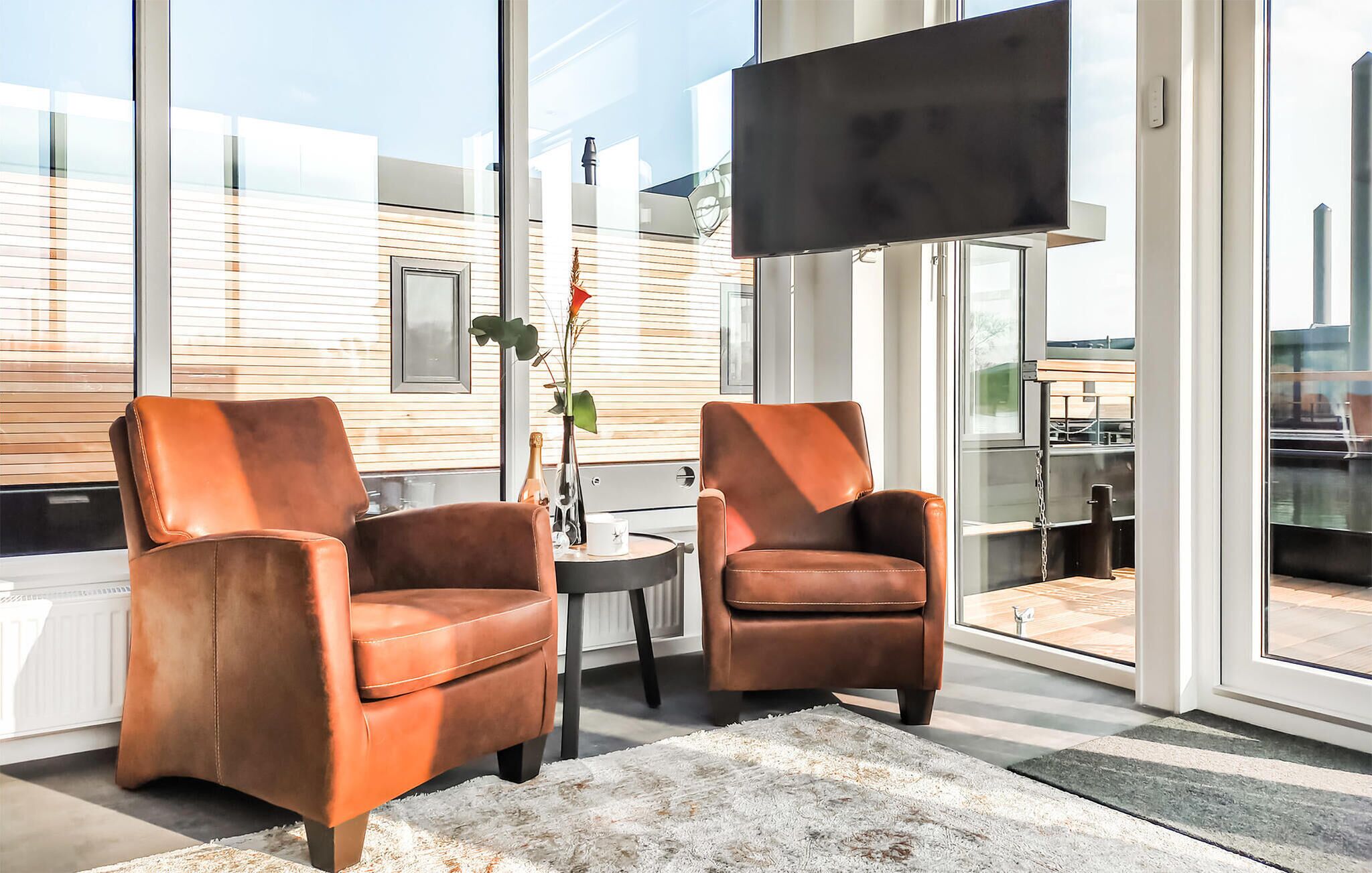 Una habitación moderna con dos sillones de cuero, una mesita y un ventanal con vistas a un edificio.
