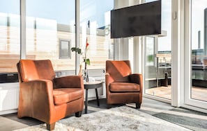 A modern room with two leather armchairs, a small table, and a large window with a view of a building.