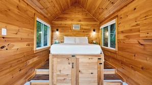 A wooden cabin with a loft bed, two windows, and a small air conditioning unit. - Creekside Cabin by Avantstay Firepit + Valley-view Deck Creek Across the Road + Trails (Jewett)