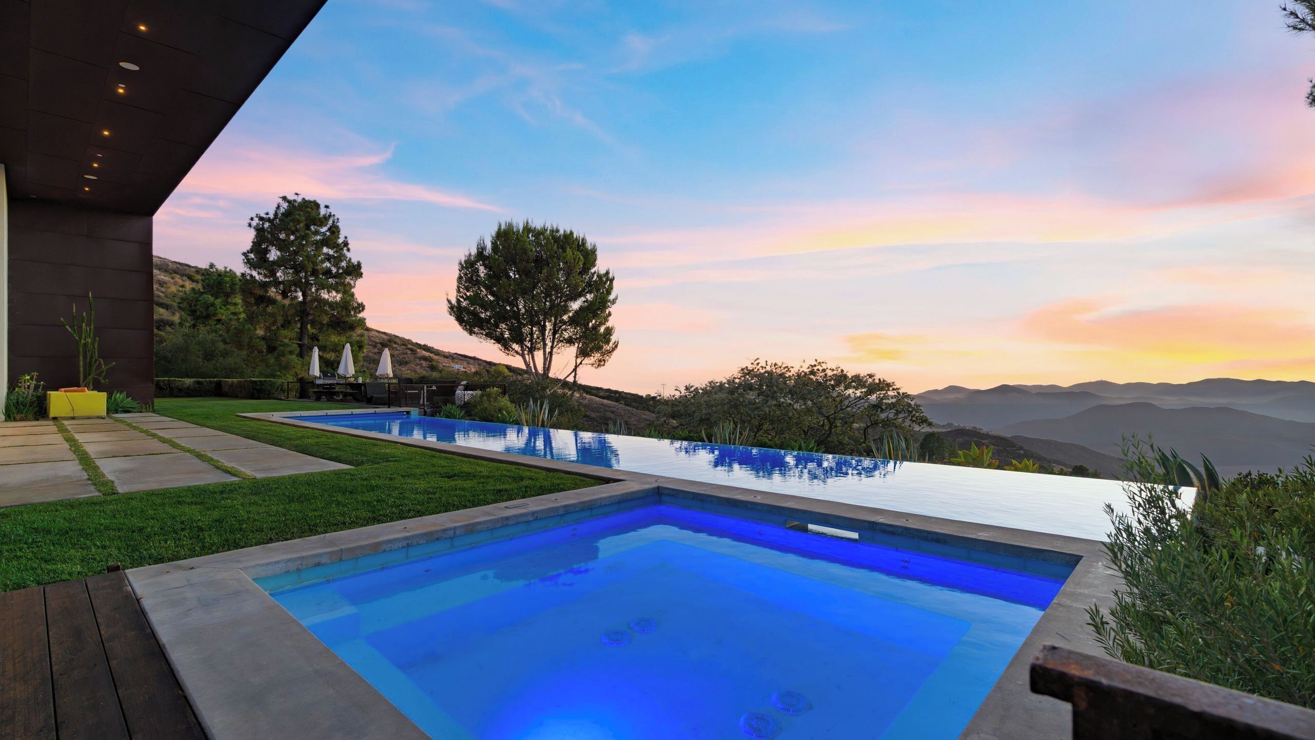 Uma piscina exterior moderna com vista clara da paisagem circundante e montanhas ao longe.