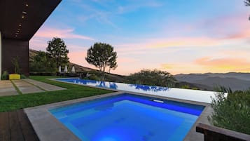 Uma piscina exterior moderna com vista clara da paisagem circundante e montanhas ao longe.