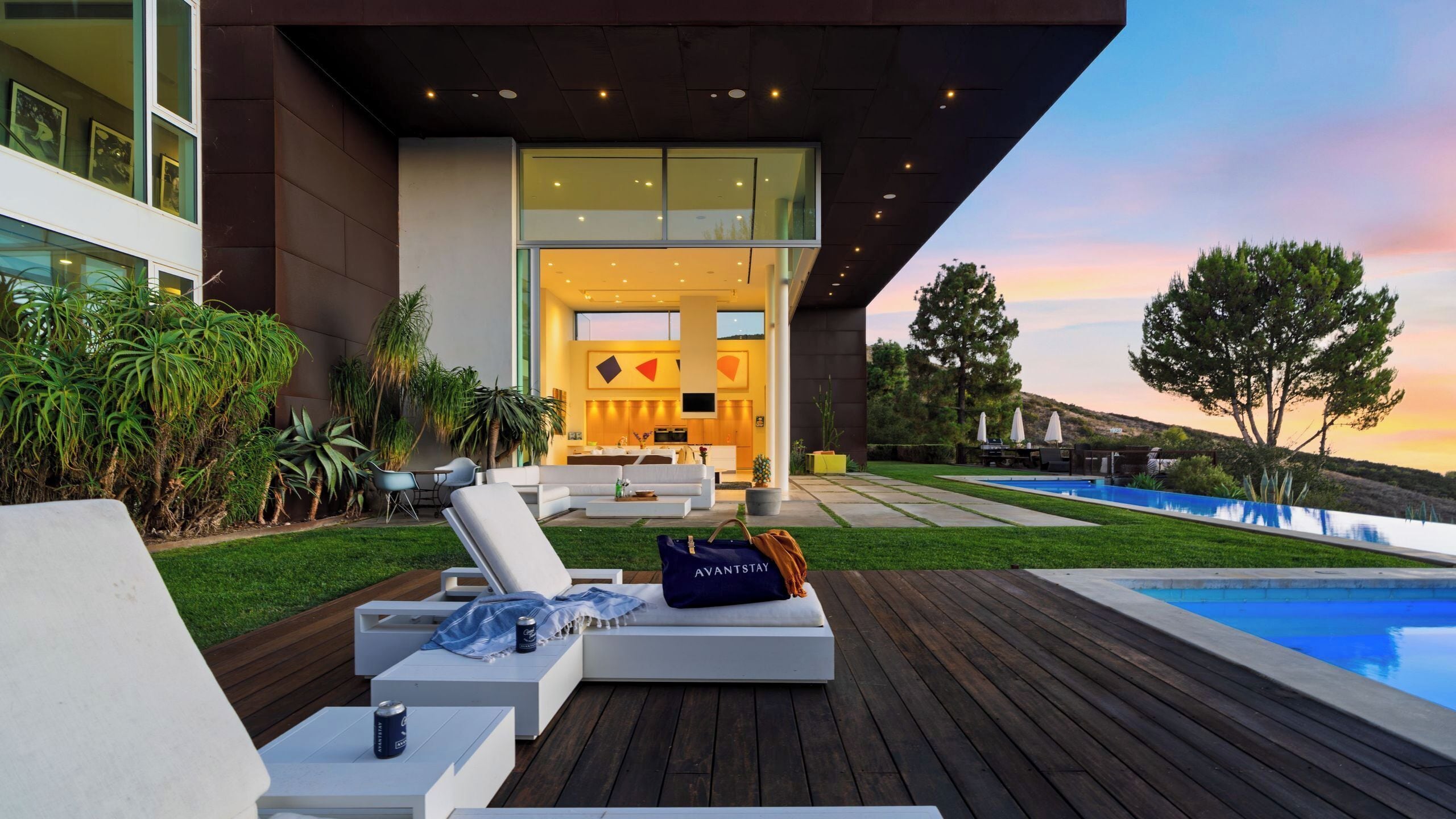 A modern outdoor living area with a pool, lounge chairs, and a dining set.