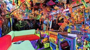 Um quarto com decoração colorida e eclética, incluindo um sofá e diversas instalações artísticas.