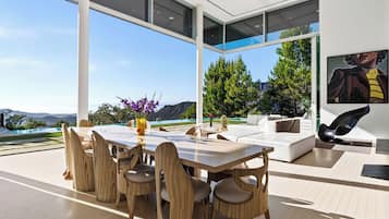 Uma área de refeições moderna ao ar livre, com uma mesa, cadeiras, um sofá e um quadro na parede.