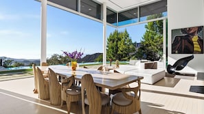 Un espace de repas extérieur moderne, avec une table et des chaises, un canapé et un tableau accroché au mur.