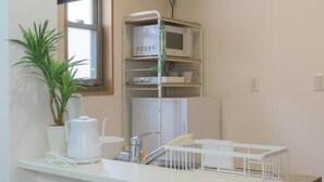 A kitchenette with a microwave, a kettle, a sink, and a plant. - Best Friend (Fukuoka City Hakataku Katakasu)
