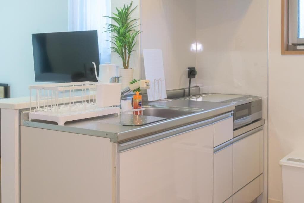 A modern kitchen with a flat-screen TV, a sink, and a dishwasher.