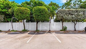 A parking lot with white picket fences and trees. - Salty Palm Retreat by Avantstay Shared Pool + Private Porch Steps to Beach + Old Town (Key West)