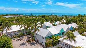 A coastal property with multiple buildings, a parking area, and a clear view of the ocean. - Salty Palm Retreat by Avantstay Shared Pool + Private Porch Steps to Beach + Old Town (Key West)