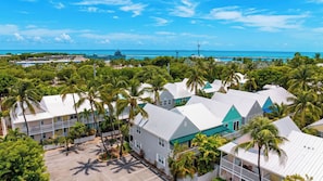 A coastal property with multiple buildings, a parking area, and a clear view of the ocean. - Salty Palm Retreat by Avantstay Shared Pool + Private Porch Steps to Beach + Old Town (Key West)
