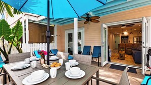 An outdoor dining area with a table set for two, chairs, and a ceiling fan. - Salty Palm Retreat by Avantstay Shared Pool + Private Porch Steps to Beach + Old Town (Key West)