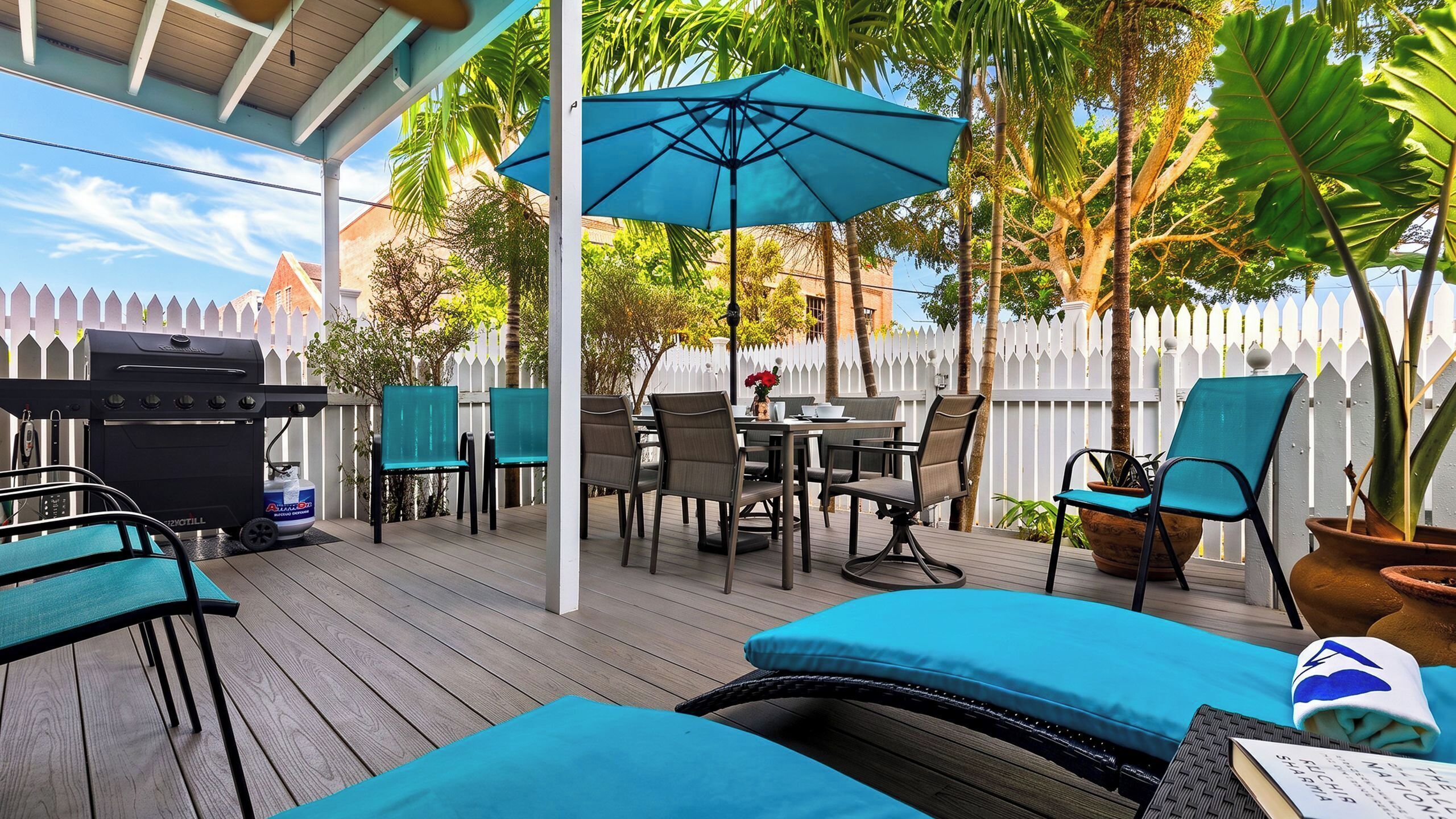 An outdoor patio area with a grill, seating, and umbrellas.