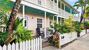 A two-story house with a porch, a chair, and a small table. - Salty Palm Retreat by Avantstay Shared Pool + Private Porch Steps to Beach + Old Town (Key West)