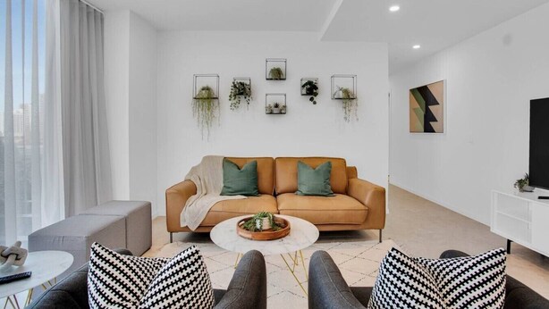 Un salon moderne avec un canapé, une table basse et des coussins à motifs.