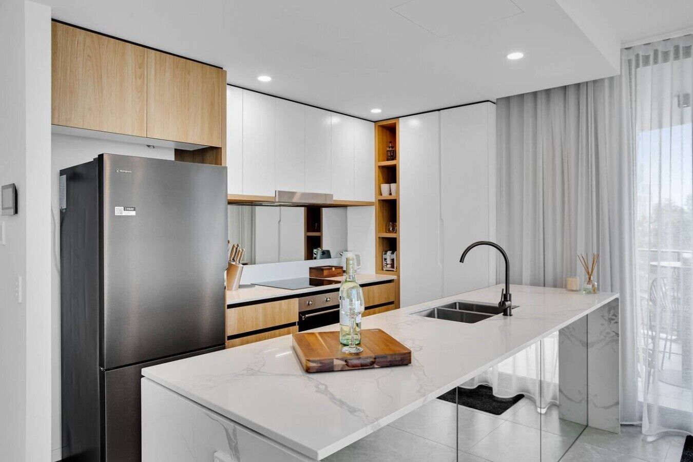 Eine moderne Küche mit Einbaukühlschrank, Marmorarbeitsplatte und elegantem Wasserhahn.