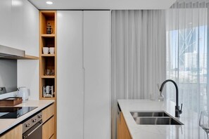 Eine moderne Küche mit Backofen, Spüle und einem Fenster mit Vorhängen.
