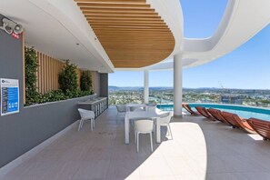 Eine Dachterrasse mit Pool, Sitzgelegenheiten im Freien und Blick auf die Stadt.