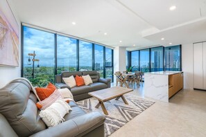 Ein modernes Wohnzimmer mit einer Couch, einem Couchtisch und einem Essbereich mit Blick auf die Stadt.